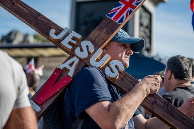 September 26, 2026, London, United Kingdom: A patriot carries a wooden cross with the inscription Jesus Saves inscribed on it during a protest against grooming gangs targeting British girls. The event organised by Together For The Children in collaboration with Football Lads on National Survivors Day stands in solidarity with survivors of child sexual abuse and sexual violence while demanding stronger child protections and legal reforms, as well as a curb on illegal migration. London United Kingdom - ZUMAs197 20260926_aaa_s197_321 Copyright: xLabxMox