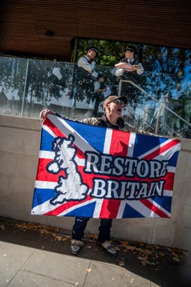 September 26, 2026, London, United Kingdom: A Restore Britain supporter holds up a Union Jack in front of New Scotland Yard during a protest against grooming gangs targeting British girls. The event organised by Together For The Children in collaboration with Football Lads on National Survivors Day stands in solidarity with survivors of child sexual abuse and sexual violence while demanding stronger child protections and legal reforms, as well as a curb on illegal migration. London United Kingdom - ZUMAs197 20260926_aaa_s197_325 Copyright: xLabxMox