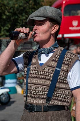 September 26, 2026, London, United Kingdom: An attendee at the King™s Cross Classic Car Boot Sale in London wears a flat cap, braces and a tank top while drinking from a beer bottle. The Kings Cross Classic Car Boot Sale returned to Granary Square and Stable Street, King™s Cross, London, for its 11th year. Held several times throughout the year, the event brings together vintage fashion, second-hand clothing, jewellery, homewares, collectables and vinyl records alongside classic cars, motorcycles and commercial vehicles. Visitors browsed stalls and traders, with many making a special effort to dress in period clothing inspired by the 1950s, 1960s and 1970s.continuing a tradition associated with the event. London United Kingdom - ZUMAs197 20260926_aaa_s197_382 Copyright: xJamesxWilloughbyx