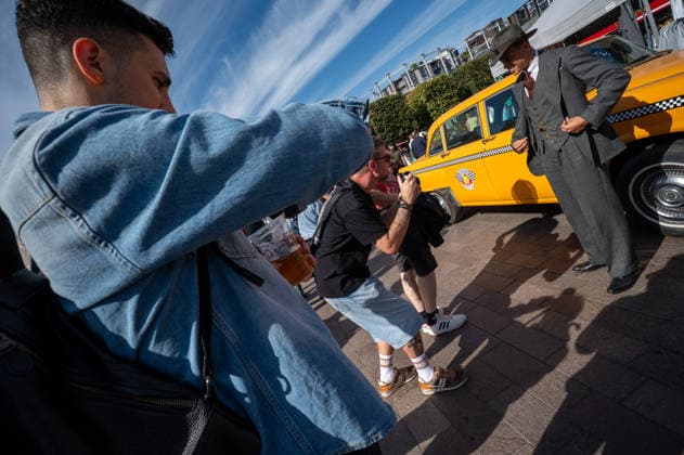 September 26, 2026, London, United Kingdom: A photographer takes a photograph of an attendee dressed in a grey suit at the King™s Cross Classic Car Boot Sale in London. The Kings Cross Classic Car Boot Sale returned to Granary Square and Stable Street, King™s Cross, London, for its 11th year. Held several times throughout the year, the event brings together vintage fashion, second-hand clothing, jewellery, homewares, collectables and vinyl records alongside classic cars, motorcycles and commercial vehicles. Visitors browsed stalls and traders, with many making a special effort to dress in period clothing inspired by the 1950s, 1960s and 1970s.continuing a tradition associated with the event. London United Kingdom - ZUMAs197 20260926_aaa_s197_371 Copyright: xJamesxWilloughbyx