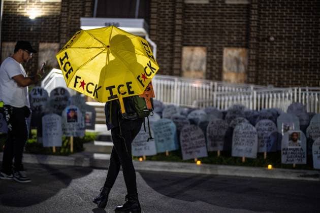 September 26, 2026, Broadview, Illinois, USA: Outside the Broadview ICE Facility, an activist holds an umbrella that reads F*ck ICE , while looking at cardboard gravestones on the lawn bearing the names of those killed since Operation Midway Blitz last year. Broadview USA - ZUMAr170 20260926_znp_r170_026 Copyright: xChrisxRihax