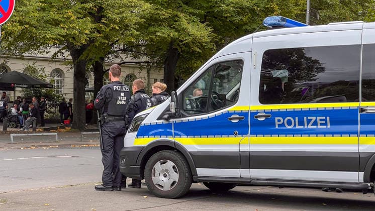 Hanover, Lower Saxony, Germany, Europe Several police officers are standing next to a police patrol car and securing the area in front of a soccer event. In the background, visitors and fans are gathered near the Waterloo Beer Garden. Stock image illustrating a police operation, security measures, public safety, soccer fans, and event management Copyright: xAymanxAlahmedx