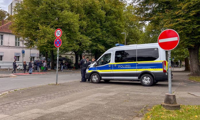 Hanover, Lower Saxony, Germany, Europe A police patrol car and several police officers are securing the area around a soccer event. Street signs, visitors, and fans are visible in the background. Stock image depicting a police operation, security measures, public order, and event management Copyright: xAymanxAlahmedx