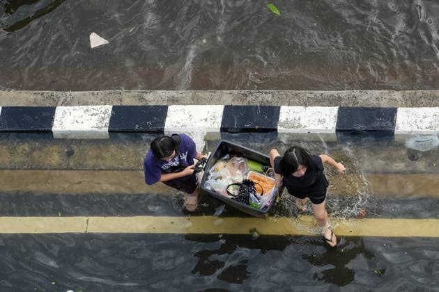 Severe floods in Bang Kapi District, Bangkok - 28 Sept 2026 A view from above of two girls carrying an open plastic container filled with food on Lat Phrao Road in Bang Kapi District. On September 26, all 50 districts of Bangkok were declared disaster-affected areas. Three days later, floodwaters still remained in parts of the city. In heavily affected areas such as Bang Kapi District, residents remained in floodwater. Bangkok Thailand Copyright: xNathaliexJamoisx xSOPAxImagesx NathalieJamois_BangKapiFlood2026-7