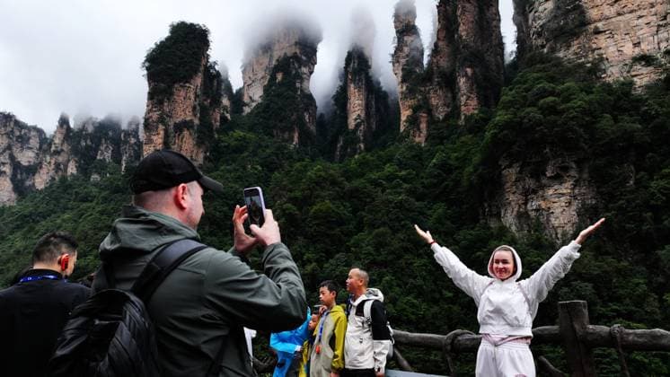 ZHANGJIAJIE, CHINA - OCTOBER 01: Tourists gather to celebrate the 77th anniversary of the founding of the People s Republic of China with cultural activities including welcome drums, blocking-door wine, hand-waving dances, cake tasting and folk songs at the Bailong Elevator viewing platform in Zhangjiajie National Forest Park on October 1, 2026 in Zhangjiajie, Hunan Province of China. Various events were held across the park to attract visitors during the National Day holiday. Copyright: xVCGx 111670911285