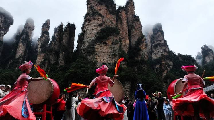 ZHANGJIAJIE, CHINA - OCTOBER 01: Tourists gather to celebrate the 77th anniversary of the founding of the People s Republic of China with activities including welcome drums, door-blocking wine, hand-waving dances, cake tasting and folk singing at the Bailong Elevator viewing platform in Zhangjiajie National Forest Park on October 1, 2026 in Zhangjiajie, Hunan Province of China. Various events were held across the scenic area to attract domestic and international visitors during the National Day holiday. Copyright: xVCGx 111670911314