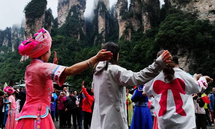 ZHANGJIAJIE, CHINA - OCTOBER 01: Tourists gather to celebrate the 77th anniversary of the founding of the People s Republic of China with colorful activities including welcome drums, blocking-door wine, hand-waving dance, cake tasting and folk songs at the Bailong Elevator viewing platform in Zhangjiajie National Forest Park on October 1, 2026 in Zhangjiajie, Hunan Province of China. Copyright: xVCGx 111670911317