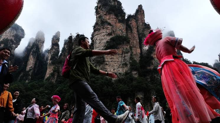 ZHANGJIAJIE, CHINA - OCTOBER 01: Tourists gather to celebrate the 77th anniversary of the founding of the People s Republic of China with activities including welcome drums, door-blocking wine, hand-waving dances, cake tasting and folk singing at the Bailong Elevator viewing platform in Zhangjiajie National Forest Park on October 1, 2026 in Zhangjiajie, Hunan Province of China. Various events were held across scenic areas to attract tourists during the National Day holiday. Copyright: xVCGx 111670911318