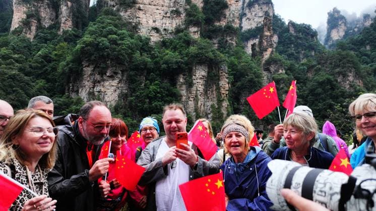 ZHANGJIAJIE, CHINA - OCTOBER 01: Tourists gather to celebrate the 77th anniversary of the founding of the People s Republic of China with colorful activities including welcome drums, blocking-door wine, hand-waving dances, cake tasting and mountain songs at Bailong Elevator viewing platform in Zhangjiajie National Forest Park on October 1, 2026 in Zhangjiajie, Hunan Province of China. Copyright: xVCGx 111670911306