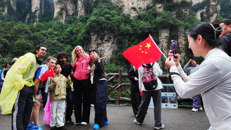 ZHANGJIAJIE, CHINA - OCTOBER 01: Tourists gather to celebrate the 77th anniversary of the founding of the People s Republic of China with cultural activities including welcome drums, blocking-door wine, hand-waving dances, cake tasting and folk singing at the Bailong Elevator viewing platform in Zhangjiajie National Forest Park on October 1, 2026 in Zhangjiajie, Hunan Province of China. Copyright: xVCGx 111670911309