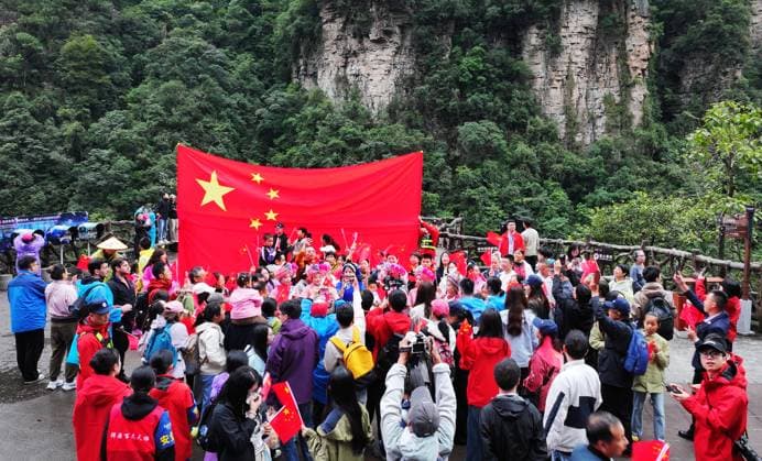 ZHANGJIAJIE, CHINA - OCTOBER 01: Tourists gather to celebrate the 77th anniversary of the founding of the People s Republic of China with colorful activities including welcome drums, door-blocking wine, hand-waving dances, cake tasting and folk singing at Bailong Elevator viewing platform in Zhangjiajie National Forest Park on October 1, 2026 in Zhangjiajie, Hunan Province of China. Copyright: xVCGx 111670911299