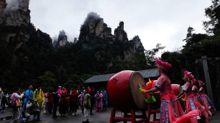 ZHANGJIAJIE, CHINA - OCTOBER 01: Tourists gather to celebrate the 77th anniversary of the founding of the People s Republic of China during colorful activities including welcome drums, door-blocking wine, hand-waving dances, cake tasting and folk songs at Bailong Elevator viewing platform in Zhangjiajie National Forest Park on October 1, 2026 in Zhangjiajie, Hunan Province of China. The event was held to attract visitors during the National Day holiday. Copyright: xVCGx 111670911294