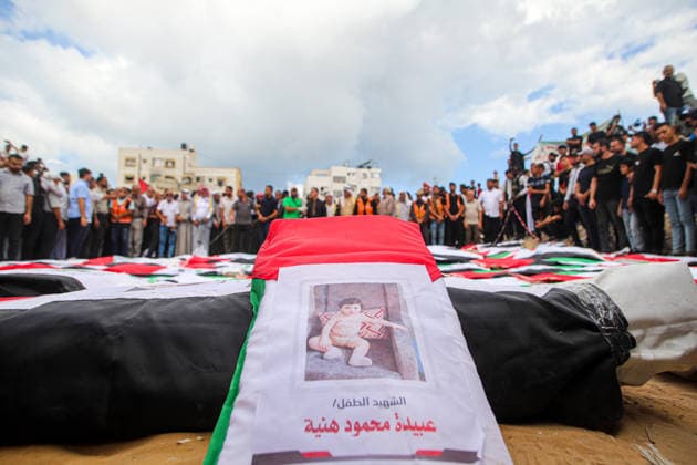 Gaza Mass Funeral For Victim A Palestinian flag-draped shroud bearing a printed photograph and identification label lies before rows of other shrouds as mourners stand in a semicircle behind them in Gaza City, Gaza Strip, on October 1, 2026. Gaza Civil Defense said the funeral was held for the remains of 105 people recovered from beneath the rubble of the Al-Taj residential complex and surrounding buildings in the Al-Yarmouk area, which were destroyed in Israeli strikes on October 25, 2023. The remains were taken for burial at Sheikh Radwan cemetery. Gaza Gaza Strip Palestinian Territories Copyright: xRamezxHabboubx