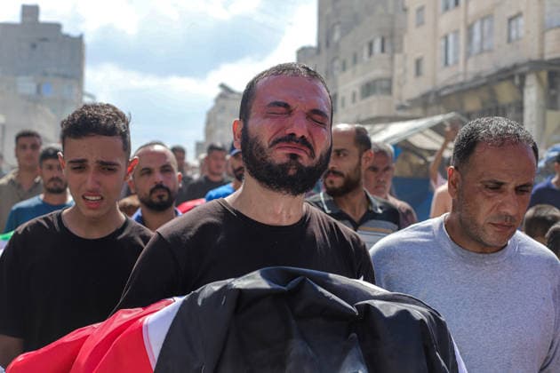Gaza Mass Funeral For Victim A Palestinian man carries a Palestinian flag-draped shrouded bundle at chest height while walking with other mourners in a funeral procession in Gaza City, Gaza Strip, on October 1, 2026. Gaza Civil Defense said the funeral was held for the remains of 105 people recovered from beneath the rubble of the Al-Taj residential complex and surrounding buildings in the Al-Yarmouk area, which were destroyed in Israeli strikes on October 25, 2023. The remains were taken for burial at Sheikh Radwan cemetery. Gaza Gaza Strip Palestinian Territories Copyright: xRamezxHabboubx