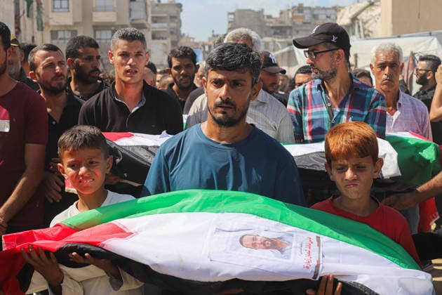 Gaza Mass Funeral For Victim A Palestinian man and two boys carry a shrouded bundle draped in a Palestinian flag and bearing a printed photograph during a funeral procession in Gaza City, Gaza Strip, on October 1, 2026. Gaza Civil Defense said the funeral was held for the remains of 105 people recovered from beneath the rubble of the Al-Taj residential complex and surrounding buildings in the Al-Yarmouk area, which were destroyed in Israeli strikes on October 25, 2023. The remains were taken for burial at Sheikh Radwan cemetery. Gaza Gaza Strip Palestinian Territories Copyright: xRamezxHabboubx