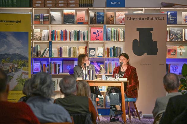 Minifestival AH0J (Literaturfestival) - Tschechien setzt über - der Kulturinitiative Literaturschiff, in der Buchhandlung Kurdirektion in Bad Ischl. Lesungen und Gespräche in Korrespondenz zum Gastauftritt Tschechiens auf der Frankfurter Buchmesse 2026. Es liest die tschechische Schriftstellerin und mehrfache Literaturpreisträgerin Radka Denemarkovich. Die Veranstaltung wird moderiert von Julia Miesenböck, fotografiert am 30.09.26. Das Bild zeigt links die Moderatorin Julia Miesenböck mit der Schriftstellerin Radka Denemarkovic im Gespräch vor Publikum 2026 - Minifestival AH0J (Literaturfestival) - Tschechien setzt über - der Kulturinitiative Literaturschiff, in der Buchhandlung Kurdirektion in Bad Ischl. Lesungen und Gespräche in K