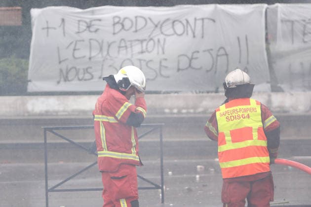 October 1, 2026, Anglet, Nouvelle Aquitaine, France: A firefighter rubs his eyes, irritated by smoke, as a colleague holds a hose during a protest outside the Lyco e Cantau in Anglet, southwestern France, on October 1, 2026, against overcrowded classes and a lack of resources. The movement, which began in the Paris region a week ago, has spread across France, with hundreds of high schools blocked. Anglet France - ZUMAb298 20261001_zsp_b298_032 Copyright: xJulesxBuonx