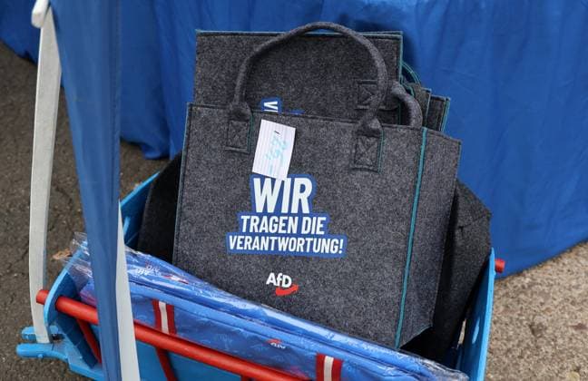 Enjoying a Bratwurst with Haseloff and Chrupalla, October 1, 2026, Doellstaedt, AfD event at Kiesling Roofing; enjoying a bratwurst with State Parliament Representative Daniel Haseloff (AfD) and AfD National Spokesperson Tino Chrupalla pictured; AfD merchandise at a booth run by the AfD Fan Shop, shown here is a tote bag with the slogan We Take Responsibility—AfD