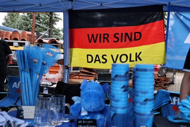 Enjoying a bratwurst with Haseloff and Chrupalla on October 1, 2026, in Doellstaedt, at an AfD event held at Kiesling Roofing, Enjoying a bratwurst with State Parliament Member Daniel Haseloff (AfD) and AfD National Spokesperson Tino Chrupalla pictured here. AfD merchandise at a booth from the AfD fan shop, including a German flag wit