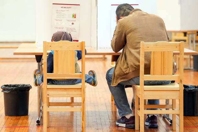 (261003) -- RIGA, Oct. 3, 2026 -- A voter fills out a ballot with his child at a polling station in Riga, Latvia, Oct. 3, 2026. Voting in the Latvian parliamentary election began on Saturday morning, with 1,428 candidates vying for 100 seats in the 15th Saeima, Latvia s parliament. (Photo by Xinhua) LATVIA-RIGA-PARLIAMENTARY ELECTION EdijsxPalens 