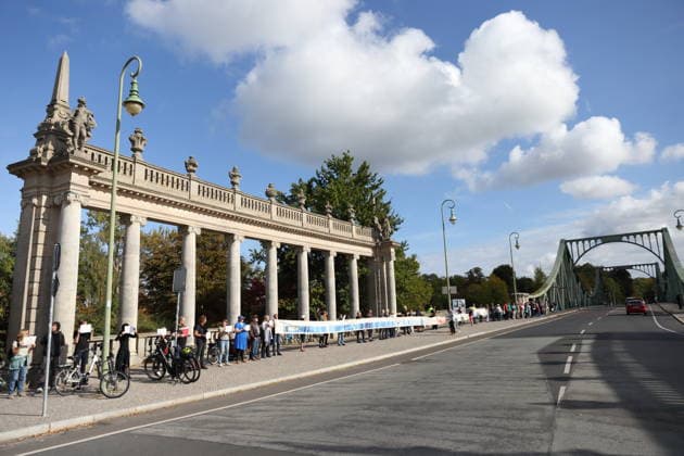 Protesters during a human chain for climate protection and democracy on the Glienicker Bridge in Potsdam, October 3, 2026. It s on fire —human chain in Potsdam