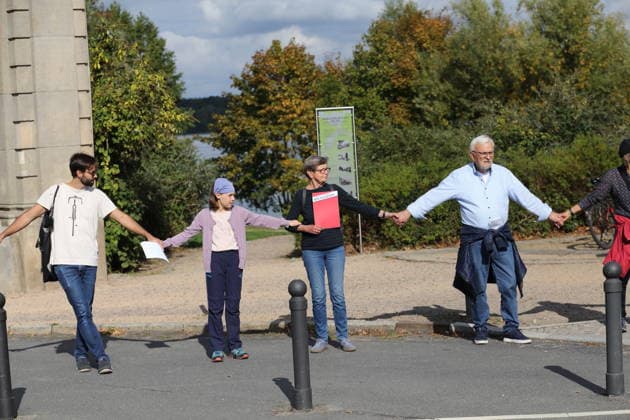 Protesters during a human chain for climate protection and democracy on the Glienicker Bridge in Potsdam, October 3, 2026. It s on fire —human chain in Potsdam