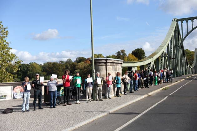 Protesters during a human chain for climate protection and democracy on the Glienicker Bridge in Potsdam, October 3, 2026. It s on fire —human chain in Potsdam
