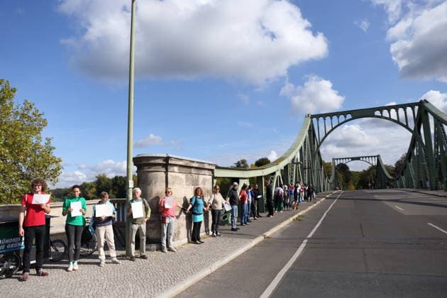 Protesters during a human chain for climate protection and democracy on the Glienicker Bridge in Potsdam, October 3, 2026. It s on fire —human chain in Potsdam