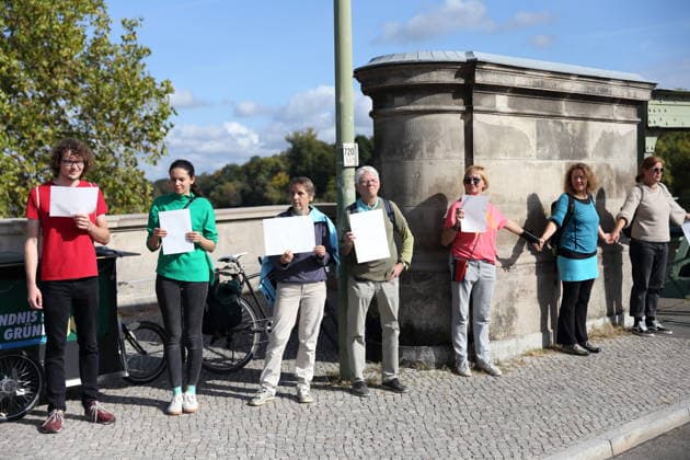 Protesters during a human chain for climate protection and democracy on the Glienicker Bridge in Potsdam, October 3, 2026. It s on fire —human chain in Potsdam