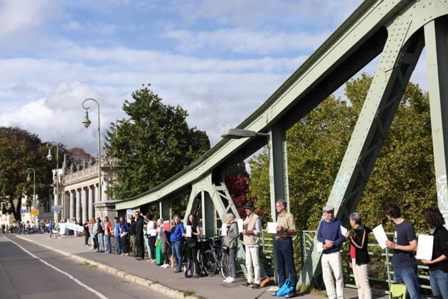 Protesters during a human chain for climate protection and democracy on the Glienicker Bridge in Potsdam, October 3, 2026. It s on fire —human chain in Potsdam