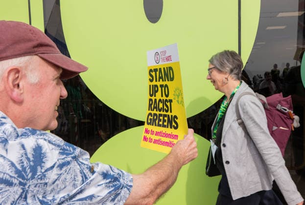 Pro-Israel rally face off against a counter-demonstration of pro-Palestine protesters outside the Party’s Autumn Conference - 03 Oct 2026 Pro Israel supporter with stand up to Racist Greens placard waves at the recent Green Manchester mayoral candidate Geraldine Coggins as she enters the Brighton conference centre during the demonstration. Activists from a pro-Israel rally face off against a counter-demonstration of pro-Palestine protesters outside the Brighton Centre, where the Green Party’s Autumn Conference is underway. Pickets lines formed as tensions flared over a highly controversial internal conference motion seeking to formally classify Zionism as Racism . Brighton United Kingdom Copyright: xGaryxRobertsx xSOPAxImagesx GROBERTS-29