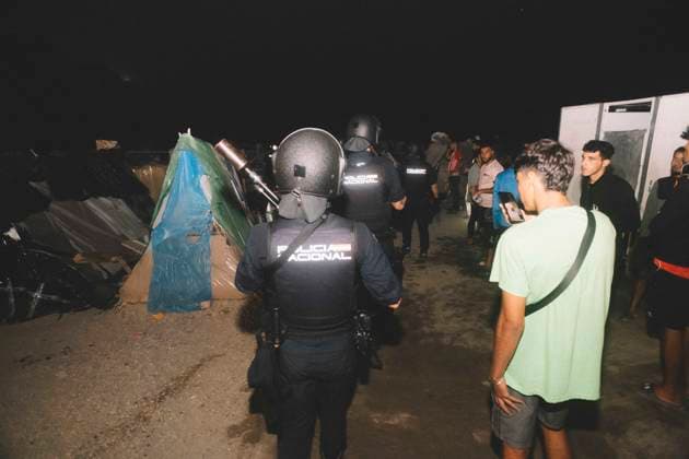 October 3, 2026, Ceuta, Ceuta, Spain: A riot police officer stands among young men and tents at a makeshift migrant camp in Ceuta at night. Riot police escorted firefighters through the camp on the night of October 3 to put out the fires that people living there use to cook their food. Thousands of migrants, most of them young Moroccan men, have been living in makeshift settlements in the Spanish North African enclave of Ceuta since a mass arrival at the end of July 2026 set off a migration and political crisis. Ceuta Spain  - ZUMAs392 20261003_zip_s392_016 Copyright: xFabianxSuspensivox
