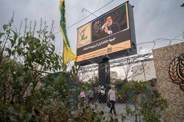 Daily Life Around A City-Square Military Training Camps Iranian people walk beneath a display featuring a portrait of the late Hezbollah Secretary-General Hassan Nasrallah alongside Persian text reading, The Self-Sacrificing Forces Front from Beirut to Baghdad, outside the second city-square military training camp for self-sacrificing forces in downtown Tehran, Iran, on October 3, 2026. The second City-Square Military Training Camp for the self-sacrificing forces was established by the Basij paramilitary force, while personnel from the Islamic Republic of Iran Army are responsible for training the volunteers. Tehran Tehran Iran  Copyright: xMortezaxNikoubazlx originalFilename: nikoubazl-dailylif261003_npHrl