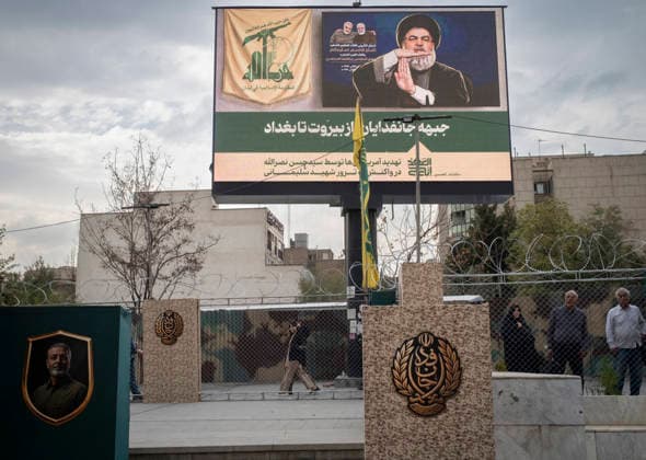 Daily Life Around A City-Square Military Training Camps A young Iranian woman makes a Victory sign as she walks beneath a display featuring a portrait of the late Hezbollah Secretary-General Hassan Nasrallah alongside Persian text reading, The Self-Sacrificing Forces Front from Beirut to Baghdad, outside the second city-square military training camp for self-sacrificing forces in downtown Tehran, Iran, on October 3, 2026. The camp was established by the Basij paramilitary force, with personnel from the Islamic Republic of Iran Army responsible for training the volunteers. Tehran Tehran Iran  Copyright: xMortezaxNikoubazlx originalFilename: nikoubazl-dailylif261003_npPd6