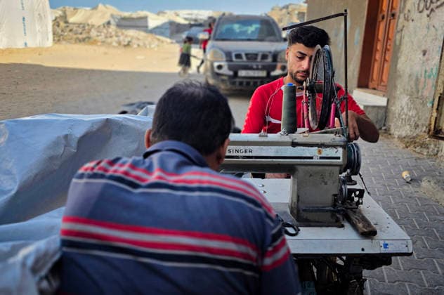 Palestinian Tailor Repairs Tent Covers for Displaced Families in Khan Younis Palestinian tailor Shaaban al-Tabash repairs and assembles tarpaulins and plastic sheets using rudimentary methods to reinforce the tents of displaced Palestinians and protect them from cold weather and rain in Khan Younis, in the southern Gaza Strip, on October 4, 2026. As winter approaches, shortages of protective supplies and the deterioration of many tents after nearly three years of war are worsening living conditions, while al-Tabash uses available materials to extend the life of shelters that have become the last refuge for thousands of displaced people. Photo by Tariq Mohammad APA Images Khan Yunis Gaza Strip Palestinian Territory 041026_Khan_Yunis_TM_01( Copyright: xapaimagesxTariqxMohammad xapaimagesx