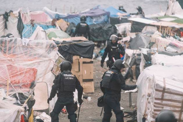 October 4, 2026, Ceuta, Ceuta, Spain: Riot police officers dismantle shelters during the eviction of the makeshift migrant camp on El Trampolin beach in Ceuta. Spanish National Police began evicting the makeshift camp on El Trampolin beach in Ceuta on October 4, where more than 3,000 migrants, most of them young Moroccan men, were living. Dozens of police vans, armoured vehicles of the Police Intervention Units (UIP), drones and boats took part in the operation. People were taken by bus to the temporary centre at the Tarajal border to be identified, and the authorities plan to clear the beach in phases before October 15. The camp grew after a mass arrival at the end of July 2026 set off a migration and political crisis. Ceuta Spain - ZUMAs392 20261004_zip_s392_012 Copyright: xFabianxSuspensivox