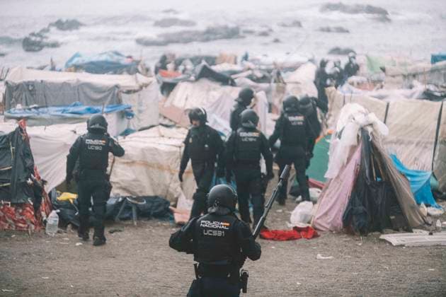 October 4, 2026, Ceuta, Ceuta, Spain: Riot police officers move into the shelters of the makeshift migrant camp on El Trampolin beach in Ceuta, with the sea behind. Spanish National Police began evicting the makeshift camp on El Trampolin beach in Ceuta on October 4, where more than 3,000 migrants, most of them young Moroccan men, were living. Dozens of police vans, armoured vehicles of the Police Intervention Units (UIP), drones and boats took part in the operation. People were taken by bus to the temporary centre at the Tarajal border to be identified, and the authorities plan to clear the beach in phases before October 15. The camp grew after a mass arrival at the end of July 2026 set off a migration and political crisis. Ceuta Spain - ZUMAs392 20261004_zip_s392_017 Copyright: xFabianxSuspensivox