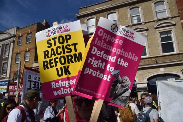 October 4, 2026, London, England, United Kingdom: A protester holds signs opposed to Reform UK and Islamophobia during the march to Cable Street against racism and fascism, marking the 90th anniversary since the Battle of Cable Street. London United Kingdom  - ZUMAv130 20261004_zip_v130_004 Copyright: xVukxValcicx