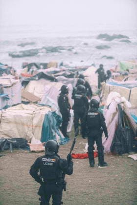 October 4, 2026, Ceuta, Ceuta, Spain: Riot police officers move into the shelters of the makeshift migrant camp on El Trampolin beach in Ceuta. Spanish National Police began evicting the makeshift camp on El Trampolin beach in Ceuta on October 4, where more than 3,000 migrants, most of them young Moroccan men, were living. Dozens of police vans, armoured vehicles of the Police Intervention Units (UIP), drones and boats took part in the operation. People were taken by bus to the temporary centre at the Tarajal border to be identified, and the authorities plan to clear the beach in phases before October 15. The camp grew after a mass arrival at the end of July 2026 set off a migration and political crisis. Ceuta Spain - ZUMAMigr 20261004_zip_s392_016 Copyright: xFabianxSuspensivox
