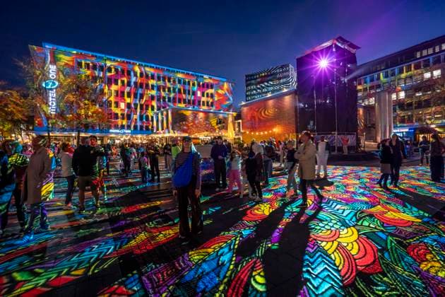 Essen Light Festival, in the city center; the light installation Diving in the Sea of Colors by Berlin-based artist Daniel Margraf illuminates the buildings on the large Kennedy Platz; visitors become part of the light art installation; North Rhine-Westphalia, Germany; Essen Light Festival