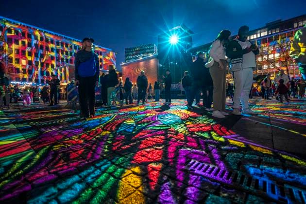 Essen Light Festival, in the city center; the light installation Diving in the Sea of Colors by Berlin-based artist Daniel Margraf illuminates the buildings on the large Kennedy Platz; visitors become part of the light art installation; North Rhine-Westphalia, Germany; Essen Light Festival