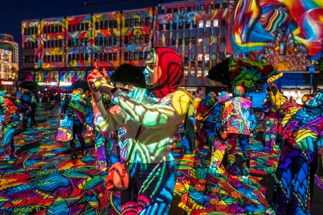 Essen Light Festival, in the city center; the light installation Diving in the Sea of Colors by Berlin-based artist Daniel Margraf illuminates the buildings on the large Kennedy Platz; visitors become part of the light art installation; North Rhine-Westphalia, Germany; Essen Light Festival