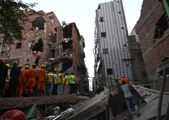 NEW DELHI, INDIA - OCTOBER 7: National Disaster Response Force (NDRF) jawans, Delhi Fire Service personnel, and local residents navigate heavy rubble during a search and rescue operation after a four-storey residential building collapsed in the New Seemapuri area of Shahdara on October 7, 2026, in New Delhi, India. The structural collapse occurred around 3:30 PM behind the local fish market, trapping multiple residents under concrete slabs and damaging two adjoining houses. At least one minor died while eight people were rescued and rushed to Rajiv Gandhi Super Speciality Hospital for emergency medical treatment as sniffer dogs and excavators worked late into the evening to locate remaining trapped survivors. (Photo by Ishant Chauhan Hindus