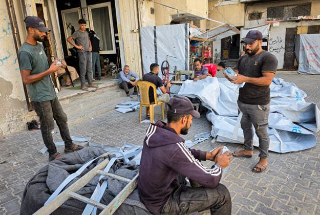Palestinian Tailor Repairs Tent Covers for Displaced Families in Khan Younis Palestinian tailor Shaaban al-Tabash repairs and assembles tarpaulins and plastic sheets using rudimentary methods to reinforce the tents of displaced Palestinians and protect them from cold weather and rain in Khan Younis, in the southern Gaza Strip, on October 4, 2026. As winter approaches, shortages of protective supplies and the deterioration of many tents after nearly three years of war are worsening living conditions, while al-Tabash uses available materials to extend the life of shelters that have become the last refuge for thousands of displaced people. Photo by Tariq Mohammad APA Images Khan Yunis Gaza Strip Palestinian Territory 041026_Khan_Yunis_TM_01( Copyright: xapaimagesxTariqxMohammad xapaimagesx