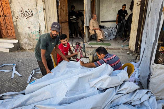 Palestinian Tailor Repairs Tent Covers for Displaced Families in Khan Younis Palestinian tailor Shaaban al-Tabash repairs and assembles tarpaulins and plastic sheets using rudimentary methods to reinforce the tents of displaced Palestinians and protect them from cold weather and rain in Khan Younis, in the southern Gaza Strip, on October 4, 2026. As winter approaches, shortages of protective supplies and the deterioration of many tents after nearly three years of war are worsening living conditions, while al-Tabash uses available materials to extend the life of shelters that have become the last refuge for thousands of displaced people. Photo by Tariq Mohammad APA Images Khan Yunis Gaza Strip Palestinian Territory 041026_Khan_Yunis_TM_01( Copyright: xapaimagesxTariqxMohammad xapaimagesx