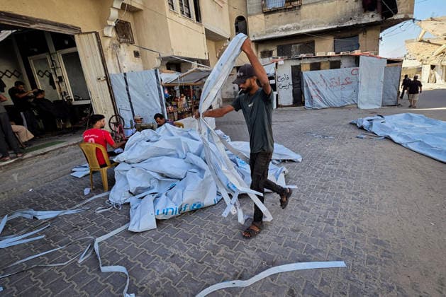 Palestinian Tailor Repairs Tent Covers for Displaced Families in Khan Younis Palestinian tailor Shaaban al-Tabash repairs and assembles tarpaulins and plastic sheets using rudimentary methods to reinforce the tents of displaced Palestinians and protect them from cold weather and rain in Khan Younis, in the southern Gaza Strip, on October 4, 2026. As winter approaches, shortages of protective supplies and the deterioration of many tents after nearly three years of war are worsening living conditions, while al-Tabash uses available materials to extend the life of shelters that have become the last refuge for thousands of displaced people. Photo by Tariq Mohammad APA Images Khan Yunis Gaza Strip Palestinian Territory 041026_Khan_Yunis_TM_01( Copyright: xapaimagesxTariqxMohammad xapaimagesx
