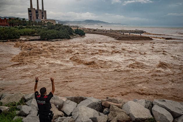 October 4, 2026, Sant Adria Del Besos, Barcelona, Spain: Police officer warns people staying at the mouth of the Besos River, north of Barcelona, swollen and laden with sediment after a night of torrential rain across Catalonia. The storm brought exceptional rainfall to the Barcelona metropolitan area, with more than 200 litres per square metre recorded in parts of the region. The Besos rose sharply overnight, prompting authorities to warn of an imminent risk of flooding. Sant Adria Del Besos Spain - ZUMAb137 20261004_fap_b137_001 Copyright: xJordixBoixareux