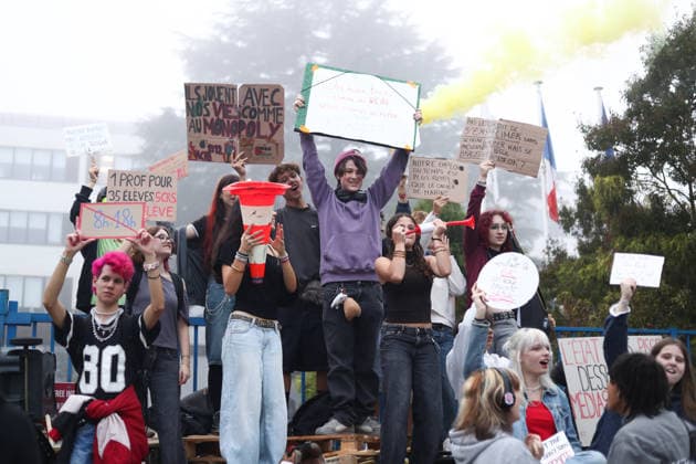 October 5, 2026, Bayonne, Nouvelle Aquitaine, France: High school students hold placards, one reading One teacher for 35 students, 5 riot police for 1 student , and a yellow smoke flare during a protest against the government outside the Reno Cassin high school in Bayonne, southwestern France, on October 5, 2026. Students have been blocking schools across France since September 21 to demand more teachers, smaller classes and better school buildings. Bayonne France - ZUMAb298 20261005_zsp_b298_007 Copyright: xJulesxBuonx