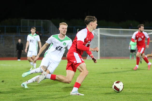 October 2, 2026 Men s Soccer 2026–2027 dachbleche24 State Cup, 2nd Round: SG Reppichau vs. Hallescher FC at Paul Greifzu Stadium, Dessau-Roßlau; Pascal Schmedemann, Halle, 24, in red, passes Oskar Schulze of Reppichau, 26, in white, at the Dessau-Roßlau Stadium in Saxony-Anhalt, Germany