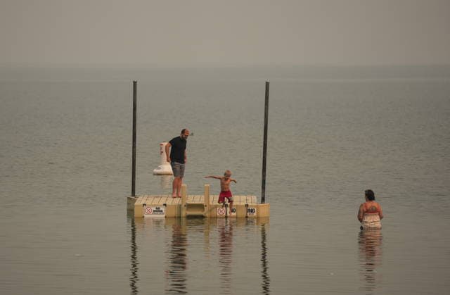 August 9, 2026, Penticton, Bc, CANADA: A young boy jumps into the water as smoke from the Bald Range wildfire envelops Okanagan Lake, in Penticton, B.C., on Sunday, Aug. 9, 2026. The Bald Range wildfire in British Columbia s south Okanagan region has forced 20,000 people out of their homes in the Peachland and Summerland areas. Penticton CANADA - ZUMAc35_ 20260809_zaf_c35_058 Copyright: xDarrylxDyckx